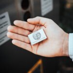 Person hält wasserabweisende Streichholzpackung in der Hand. Vor einem Grablicht Service Point der Firma Vater & Sohn Grablicht GmbH